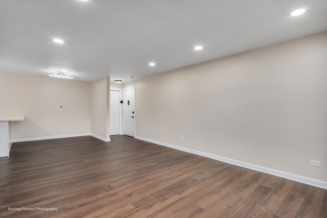 unfurnished living room with baseboards, dark wood-type flooring, and recessed lighting