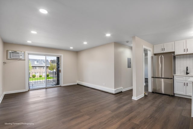 unfurnished living room featuring a baseboard radiator, baseboards, dark wood finished floors, electric panel, and recessed lighting
