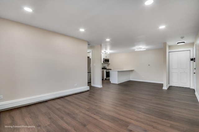 unfurnished living room with dark wood-style floors, baseboards, recessed lighting, and a baseboard heating unit