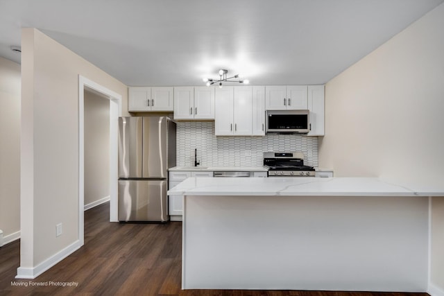 kitchen featuring stainless steel appliances, a sink, tasteful backsplash, and dark wood-style flooring