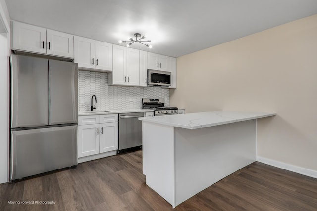 kitchen with stainless steel appliances, a sink, white cabinets, and dark wood-style flooring