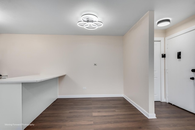 unfurnished dining area with dark wood finished floors and baseboards