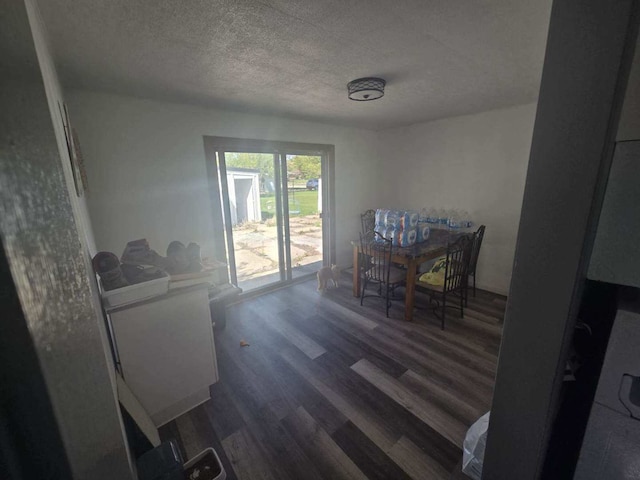dining room with a textured ceiling and dark wood finished floors