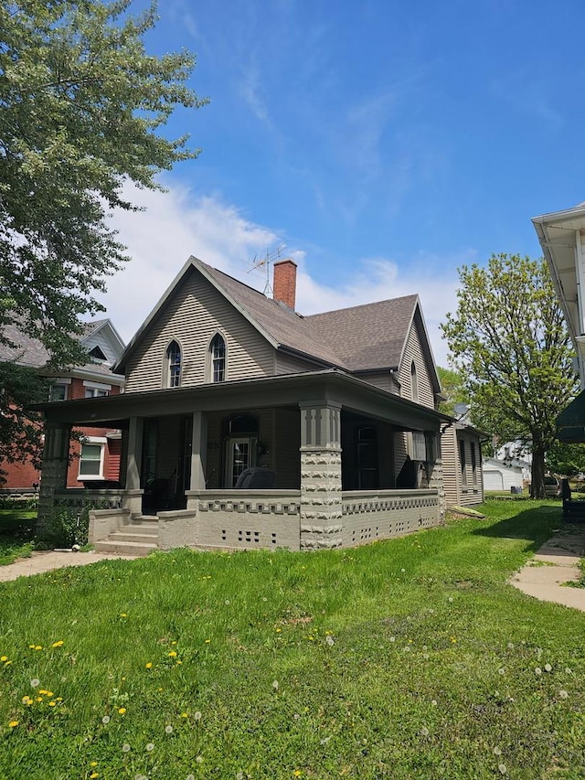 view of front of home with a front yard, a chimney, and a porch