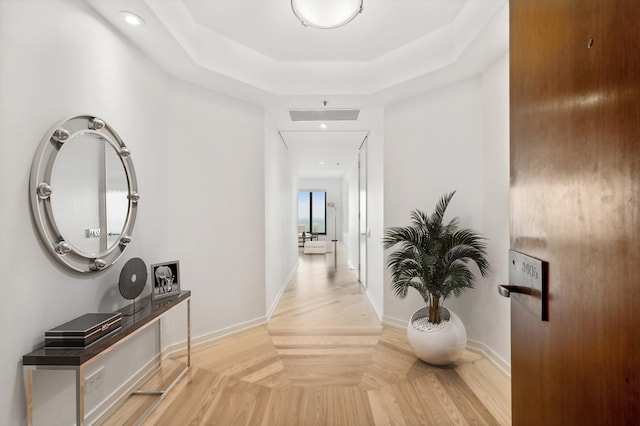 corridor with baseboards, a raised ceiling, attic access, and recessed lighting