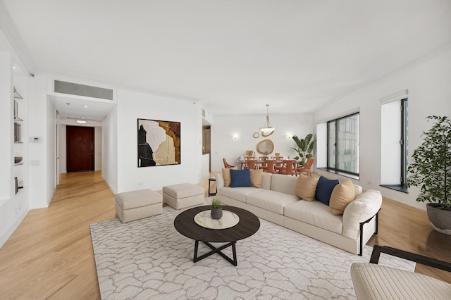 living area with light wood-style flooring, a chandelier, and baseboards