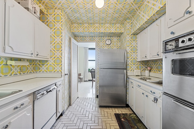 kitchen with stainless steel appliances, white cabinetry, light countertops, and an ornate ceiling