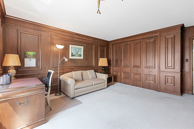 living area featuring light carpet, a desk, and wooden walls
