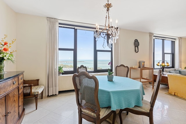 dining room featuring a chandelier, plenty of natural light, light tile patterned floors, and a water view