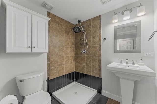 bathroom with a stall shower, toilet, and a sink