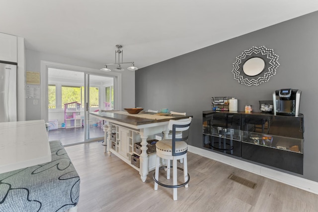 dining space featuring light wood-style floors and baseboards