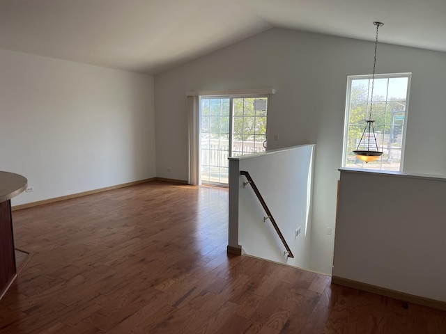 unfurnished living room featuring wood finished floors, lofted ceiling, and baseboards
