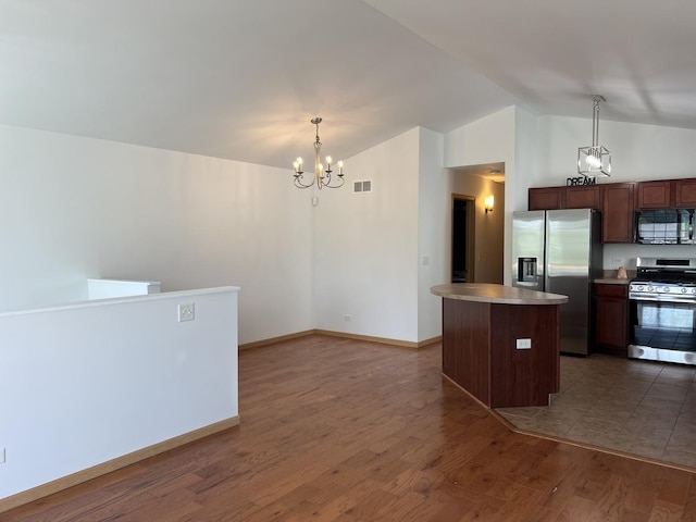 kitchen featuring appliances with stainless steel finishes, a chandelier, lofted ceiling, a center island, and wood finished floors