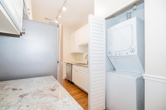 laundry area featuring stacked washer and clothes dryer and light wood finished floors
