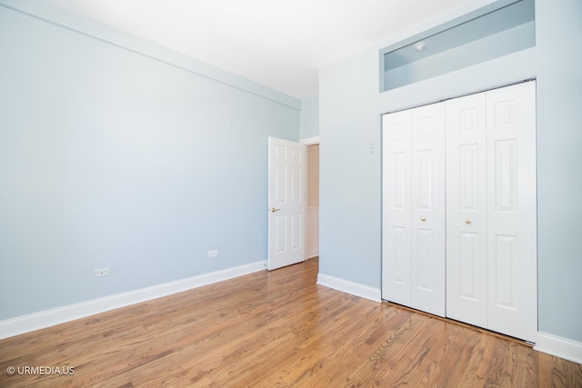 unfurnished bedroom with light wood-style floors, baseboards, and a closet