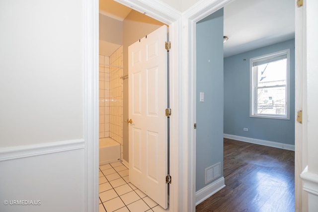 corridor featuring baseboards and light tile patterned floors