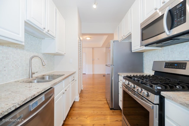 kitchen featuring stainless steel appliances, a sink, white cabinetry, and light wood-style floors