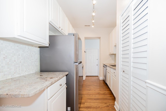 kitchen with stainless steel appliances, backsplash, white cabinets, and light wood-type flooring