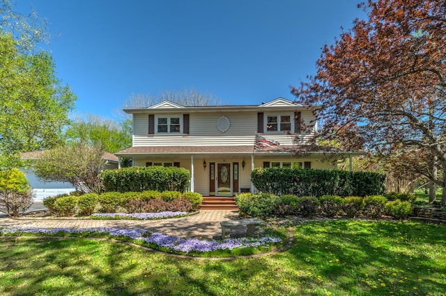 traditional-style house featuring a front lawn and covered porch