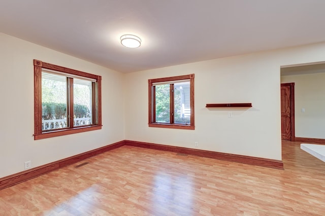 spare room with light wood-style flooring, healthy amount of natural light, and baseboards