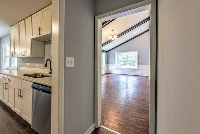 kitchen with dishwasher, a sink, vaulted ceiling, dark wood-type flooring, and white cabinetry