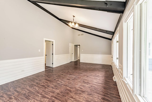 unfurnished living room featuring wainscoting, a chandelier, dark wood-style floors, and plenty of natural light