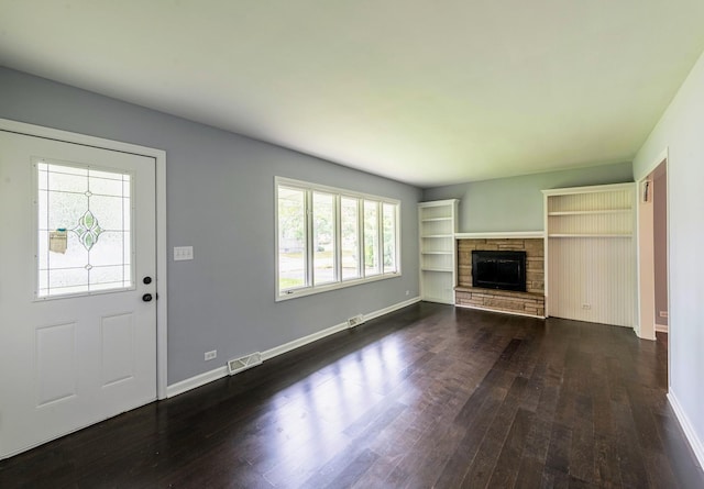 unfurnished living room featuring dark wood-type flooring, a fireplace, and baseboards