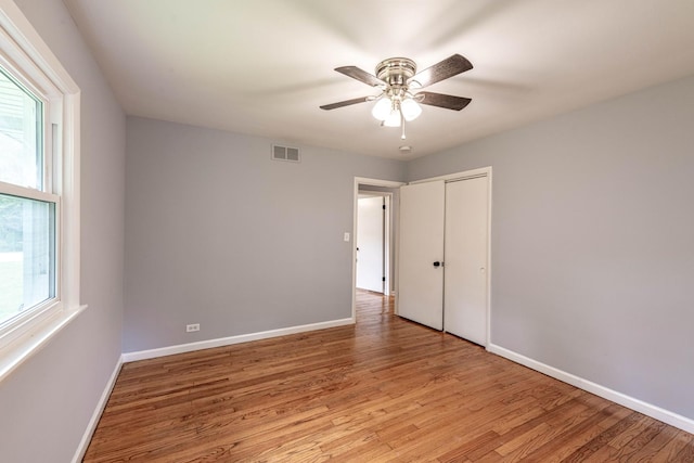unfurnished bedroom featuring light wood-style flooring, baseboards, and a closet