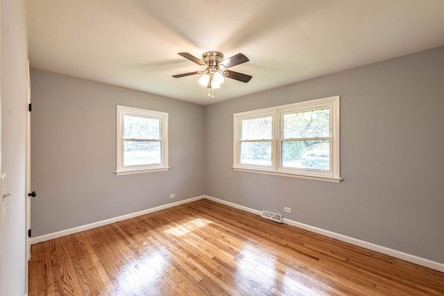 unfurnished room featuring healthy amount of natural light, baseboards, wood finished floors, and a ceiling fan