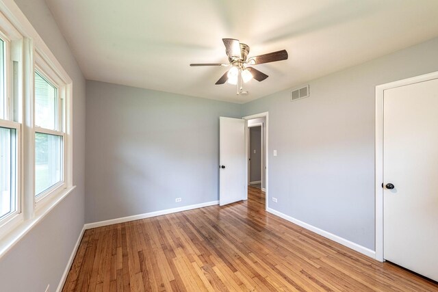 unfurnished bedroom with multiple windows, baseboards, light wood finished floors, and a ceiling fan