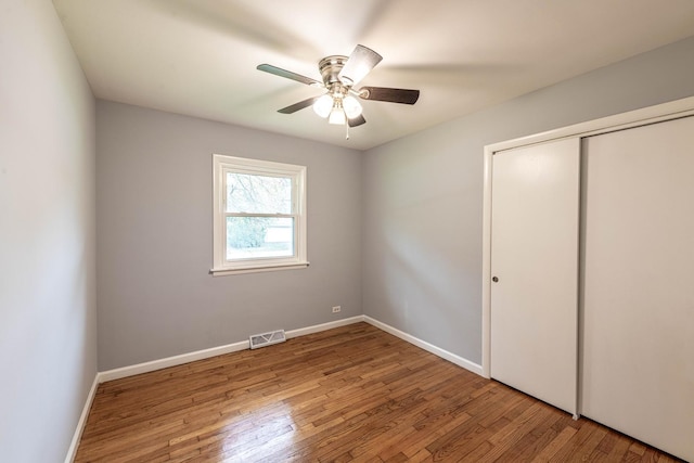 unfurnished bedroom with wood finished floors, a closet, and baseboards