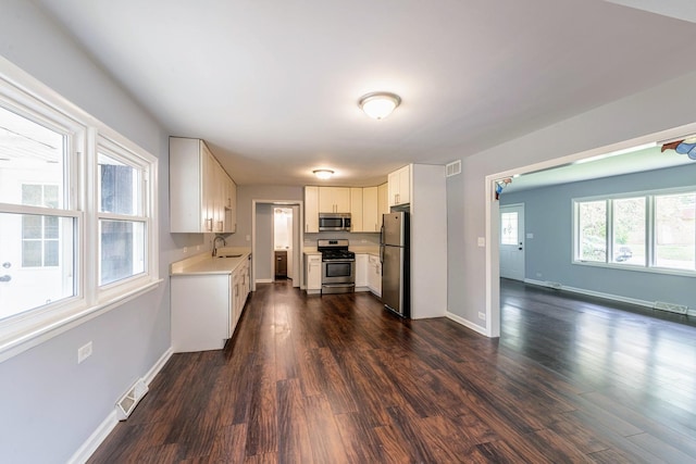 kitchen featuring stainless steel appliances, a sink, light countertops, and dark wood-style floors