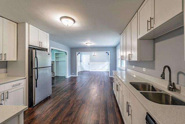 kitchen featuring freestanding refrigerator, a sink, dark wood-style flooring, white cabinetry, and light stone countertops