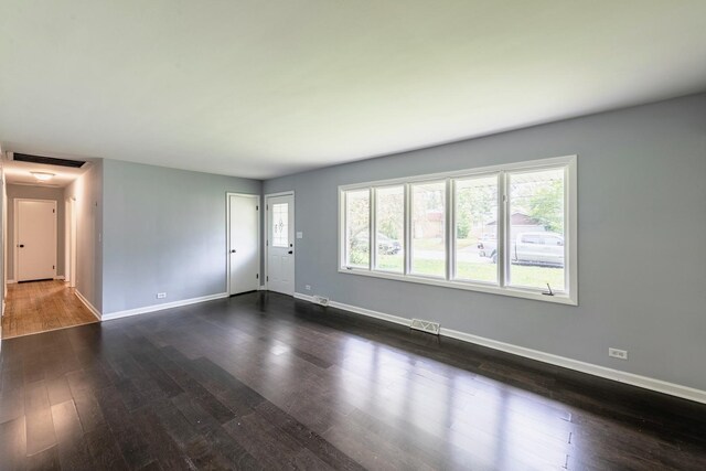unfurnished living room with baseboards and dark wood-type flooring