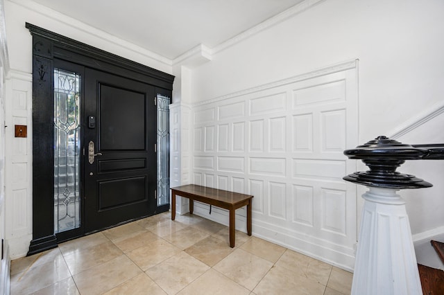 entryway featuring crown molding, light tile patterned floors, and a decorative wall