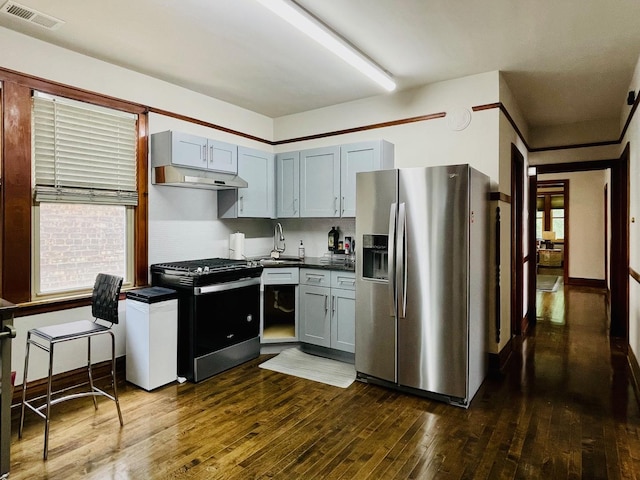 4623 S Harding Ave, Chicago, IL 60632 - kitchen with appliances with stainless steel finishes, dark countertops, dark wood-style floors, a sink, and extractor fan