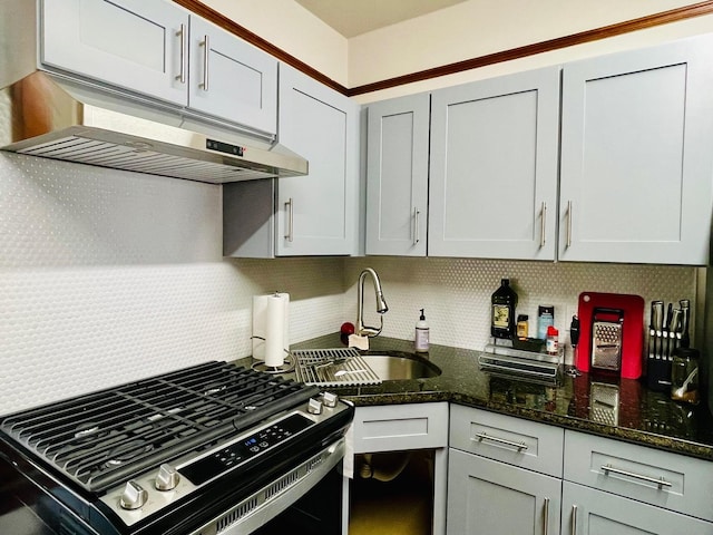 4623 S Harding Ave, Chicago, IL 60632 - kitchen with stainless steel gas stove, tasteful backsplash, a sink, dark stone countertops, and under cabinet range hood