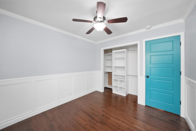 unfurnished bedroom featuring a decorative wall, wood finished floors, crown molding, a closet, and wainscoting
