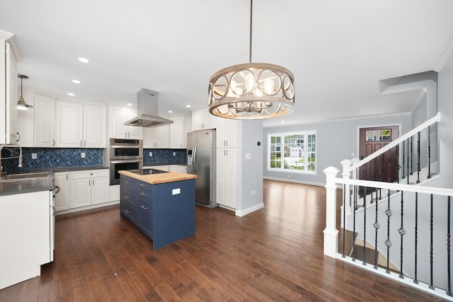 kitchen with butcher block countertops, island range hood, appliances with stainless steel finishes, a sink, and white cabinetry