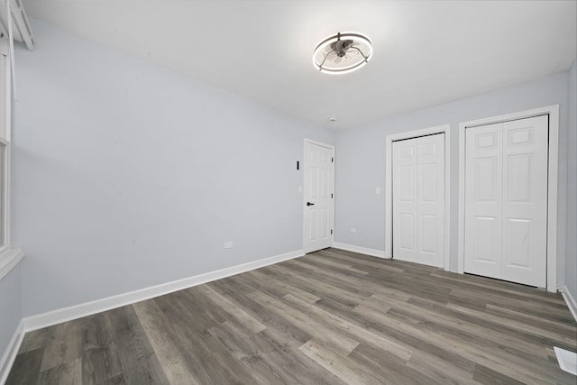 631 Fenton Ave, Romeoville, IL 60446 - unfurnished bedroom featuring multiple closets, baseboards, and wood finished floors