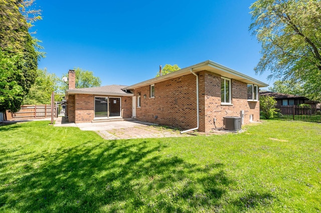 rear view of property featuring a chimney, brick siding, central air condition unit, and a patio
