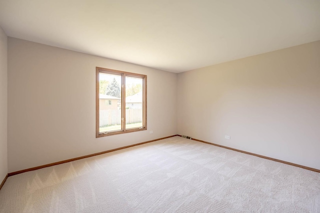 unfurnished room featuring light carpet and baseboards
