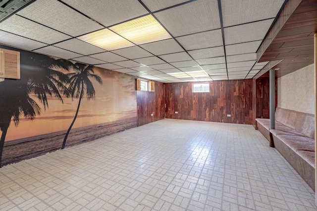 basement with brick patterned floors, wooden walls, and a paneled ceiling