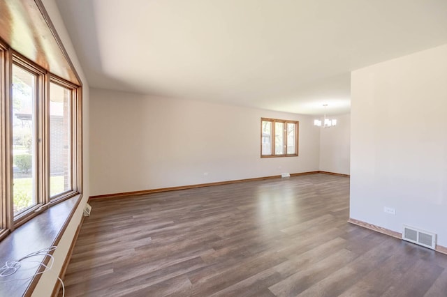 unfurnished room with a chandelier, dark wood-style floors, and baseboards
