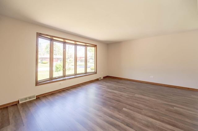 unfurnished room with dark wood finished floors and baseboards