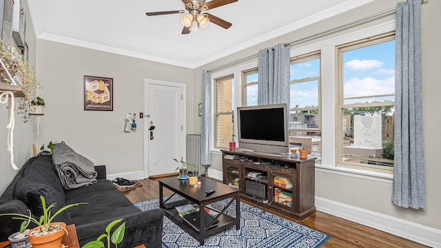living room featuring baseboards, ceiling fan, crown molding, and wood finished floors
