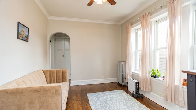 living area featuring radiator, a ceiling fan, ornamental molding, plenty of natural light, and dark wood-style flooring