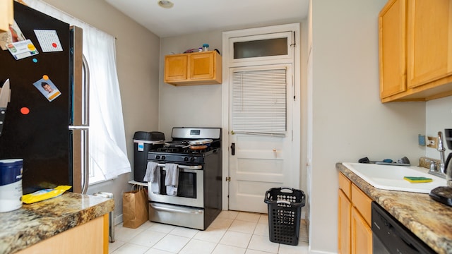 kitchen with stainless steel appliances, light tile patterned flooring, light brown cabinetry, and a sink