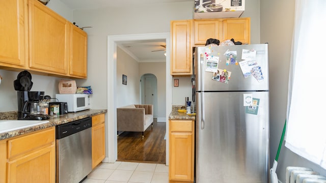 kitchen featuring appliances with stainless steel finishes, radiator heating unit, arched walkways, crown molding, and light brown cabinets