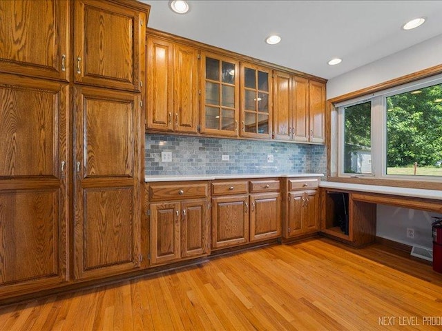 48W142 Milnamow Dr, Maple Park, IL 60151 - kitchen featuring built in desk, brown cabinets, light wood-style floors, light countertops, and decorative backsplash